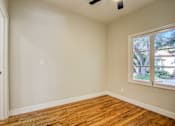Thumbnail 11 of 16 - A room with a window and wooden floors.