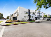 Thumbnail 5 of 5 - A white building with black accents sits on a street corner.