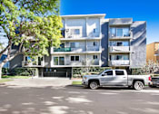 Thumbnail 17 of 17 - A silver truck is parked in front of a modern apartment building.