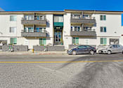 Thumbnail 1 of 13 - Two cars parked in front of a white apartment building.