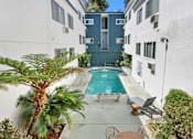 Thumbnail 6 of 13 - A pool surrounded by a patio with chairs and a palm tree.