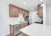 Thumbnail 3 of 18 - A kitchen with a white countertop and wooden cabinets.