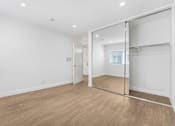 Thumbnail 6 of 18 - A room with a sliding glass door and wooden flooring.