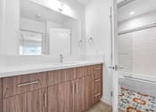Thumbnail 7 of 18 - A bathroom with a sink, mirror, and wooden cabinets.