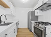 Thumbnail 5 of 19 - A modern kitchen with white cabinets and stainless steel appliances.