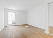 Thumbnail 6 of 19 - A room with wooden floors and white walls.