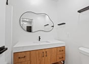 Thumbnail 7 of 19 - A white sink with a black faucet and a mirror above it.