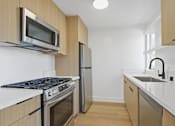 Thumbnail 13 of 19 - A kitchen with a stove, microwave, dishwasher, and sink.