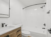 Thumbnail 16 of 19 - A white bathroom with a toilet, sink, and bathtub.
