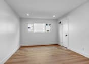 Thumbnail 24 of 29 - A room with a wooden floor and a white door.