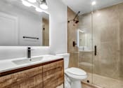 Thumbnail 25 of 29 - A modern bathroom with a white sink and toilet.