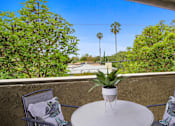Thumbnail 8 of 29 - A table with a plant on it and two chairs with towels draped over them.