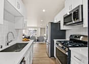 Thumbnail 11 of 29 - A modern kitchen with white cabinets and black appliances.