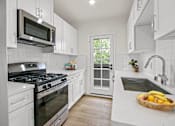 Thumbnail 14 of 29 - A kitchen with white cabinets and a stainless steel stove top.