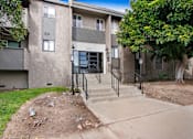 Thumbnail 6 of 29 - A concrete building with a black railing and steps leading up to the entrance.