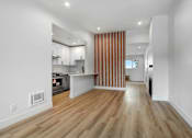 Thumbnail 2 of 29 - A modern kitchen with wooden floors and white walls.
