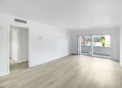 Thumbnail 1 of 14 - A room with a white wall and a window with a view of trees and a building outside.