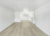 Thumbnail 3 of 14 - A long, empty hallway with wooden floors and white walls.