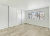 Thumbnail 6 of 14 - A room with white walls, a window with blinds, and a wooden floor.