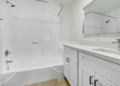 Thumbnail 7 of 14 - A white bathroom with a sink, mirror, and bathtub.