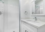 Thumbnail 9 of 14 - A white bathroom with a sink and mirror.