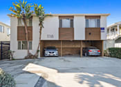 Thumbnail 1 of 3 - A modern two-story apartment building with a garage and a car parked in front.
