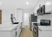 Thumbnail 1 of 12 - a kitchen with white cabinets and black appliances and white counter tops