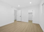 Thumbnail 7 of 12 - a living room with white walls and wooden floors and white doors