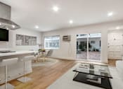 Thumbnail 1 of 32 - A modern kitchen with white cabinets and a dining area with a table set for four.