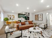 Thumbnail 11 of 32 - A living room with a brown sofa and a white coffee table.