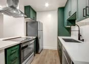 Thumbnail 6 of 32 - a kitchen with green cabinets and white counters and a stainless steel refrigerator