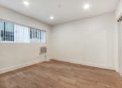 Thumbnail 8 of 32 - a living room with white walls and wood flooring and a window