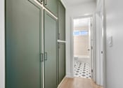 Thumbnail 25 of 32 - A hallway with a white door and a black and white tiled floor.