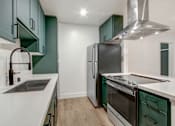 Thumbnail 15 of 32 - A modern kitchen with green cabinets and stainless steel appliances.