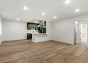 Thumbnail 14 of 32 - A spacious room with wooden flooring and a kitchenette in the corner.