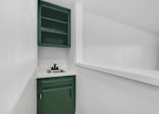 Thumbnail 22 of 29 - A green cabinet with a white sink and a white shelf.