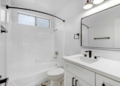 Thumbnail 24 of 29 - A white bathroom with a toilet, sink, and bathtub.