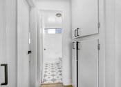 Thumbnail 25 of 29 - A hallway with white walls and a black door.