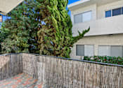 Thumbnail 2 of 21 - A building with a wooden fence and a tree in front of it.