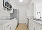 Thumbnail 4 of 21 - A kitchen with white cabinets and a black countertop.
