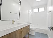 Thumbnail 7 of 21 - A white bathroom with a marble counter top and a toilet.