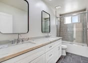 Thumbnail 13 of 21 - A white bathroom with a double sink and a toilet.