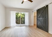 Thumbnail 14 of 21 - A room with a sliding door and a ceiling fan.