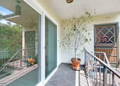 Thumbnail 15 of 21 - A balcony with a glass door and a potted plant.