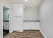 Thumbnail 17 of 21 - A kitchen with white cabinets and a wooden floor.