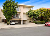Thumbnail 20 of 21 - A white two-story apartment building with a red car parked in front.