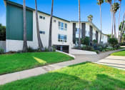Thumbnail 11 of 23 - a white building with palm trees and a sidewalk in front of it