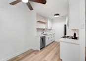 Thumbnail 13 of 23 - A kitchen with white cabinets and a wooden ceiling fan.