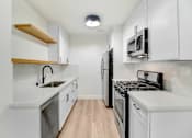 Thumbnail 12 of 23 - A kitchen with white cabinets and black appliances.