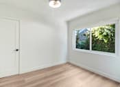 Thumbnail 18 of 23 - A white door is on the left and a window with a view of trees is on the right.